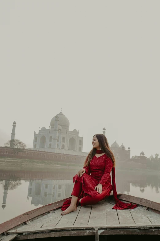 a woman is sitting on a dock next to a lake