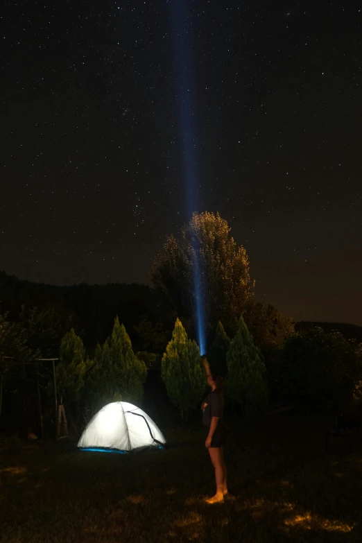 a man standing next to a tent under the stars