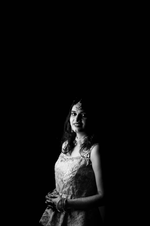 a woman standing on the side of a black background wearing a dress