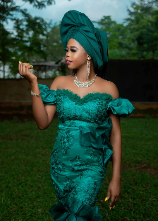 a woman in a green dress and gold accessories on a grassy field