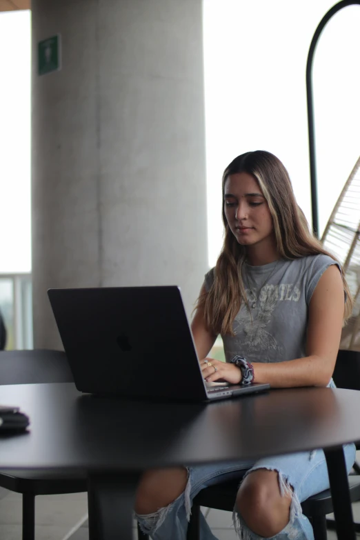 a woman is sitting at a table using her laptop