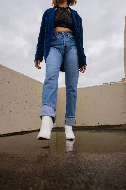 a woman with white boots wearing a blue coat and blue jeans