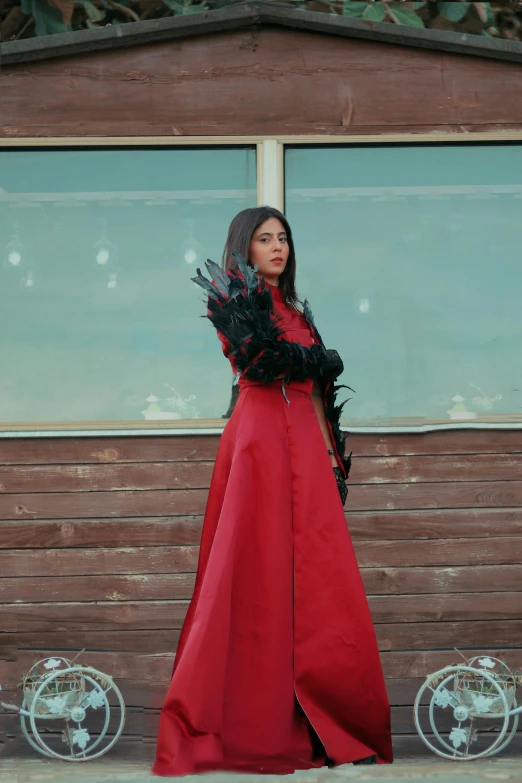 a woman in red is standing by a building