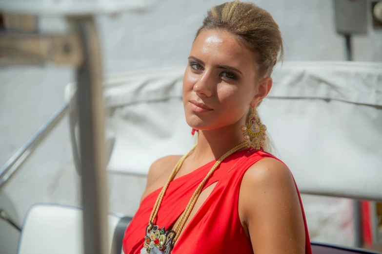 the woman is wearing a large gold necklace and a long orange dress