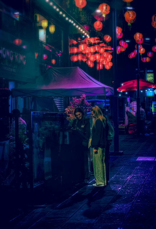 two people stand in a shopping area lit up by many hanging lights