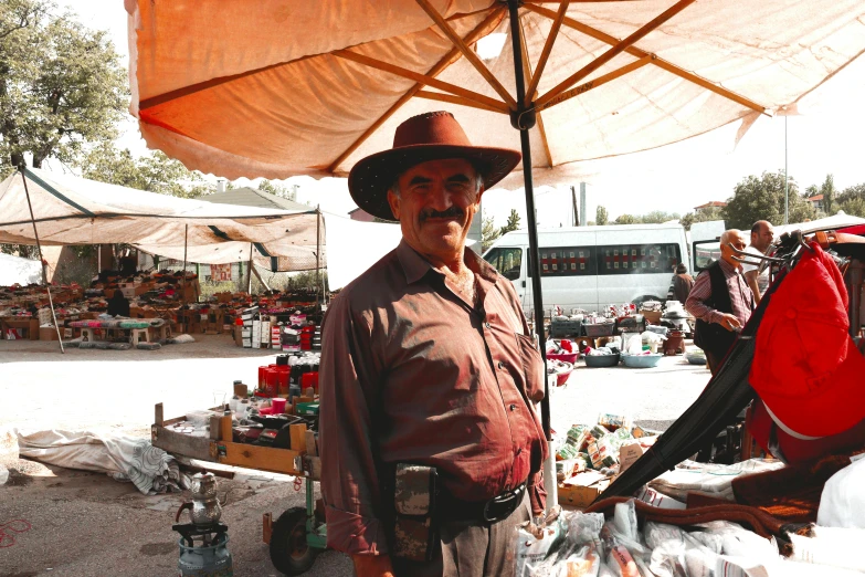 a man wearing a hat standing in front of an umbrella