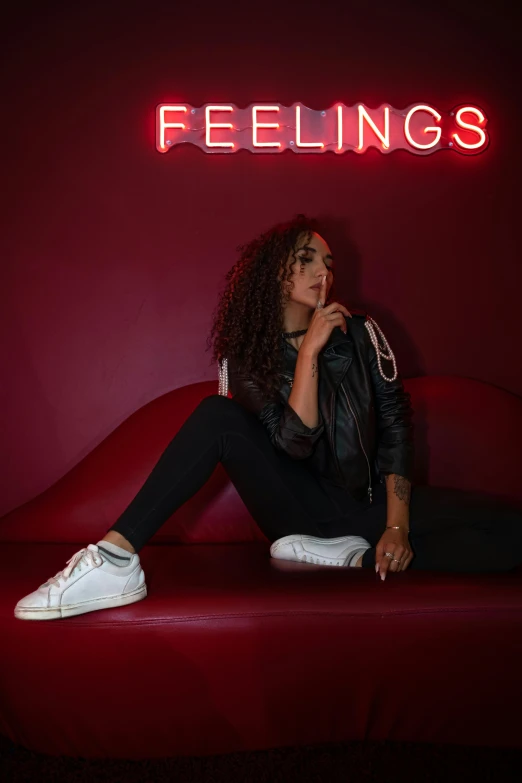 a young woman sitting on a red couch in front of a neon sign