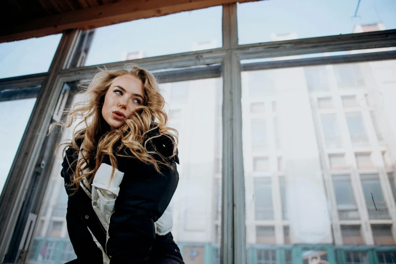 a young woman sitting on a windowsill looking in