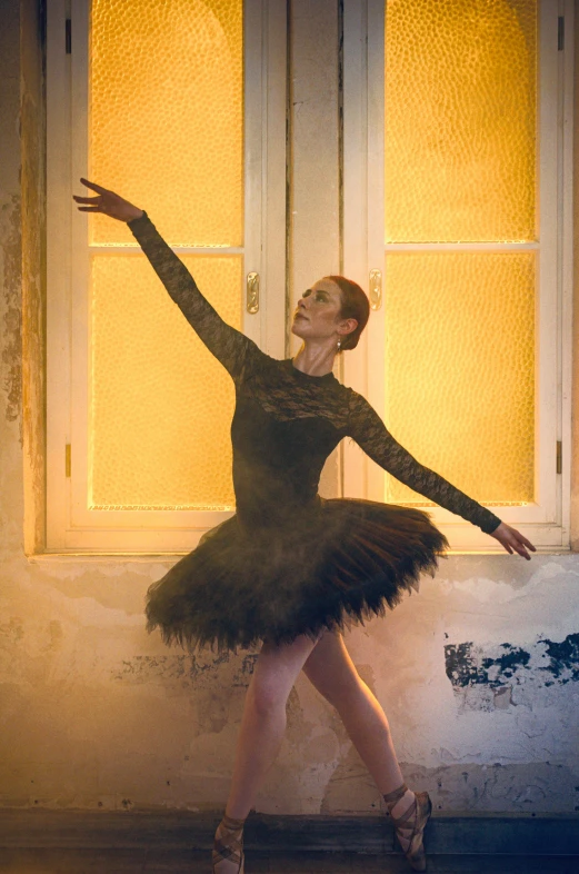 a young ballerina stretches out of an empty room in front of a window