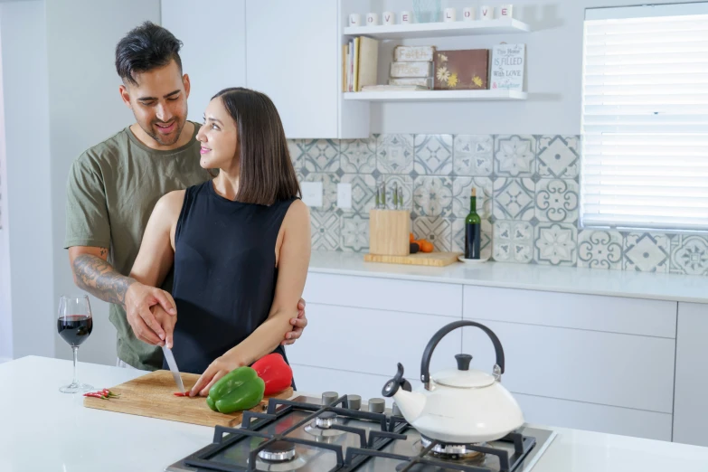 man and woman standing next to each other in a kitchen preparing food