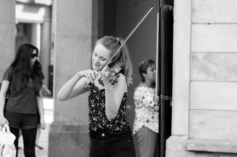 a lady playing violin while a girl looks on