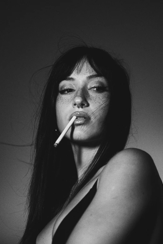 the woman poses with a cigarette in her mouth