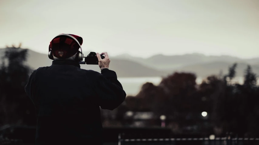 a person standing next to a fence taking pictures