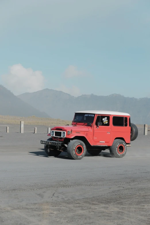 a red jeep is parked on the sand