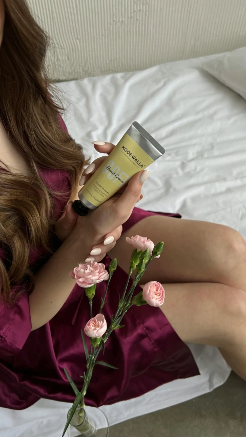 a woman sitting on her bed in a pink dress reading a book