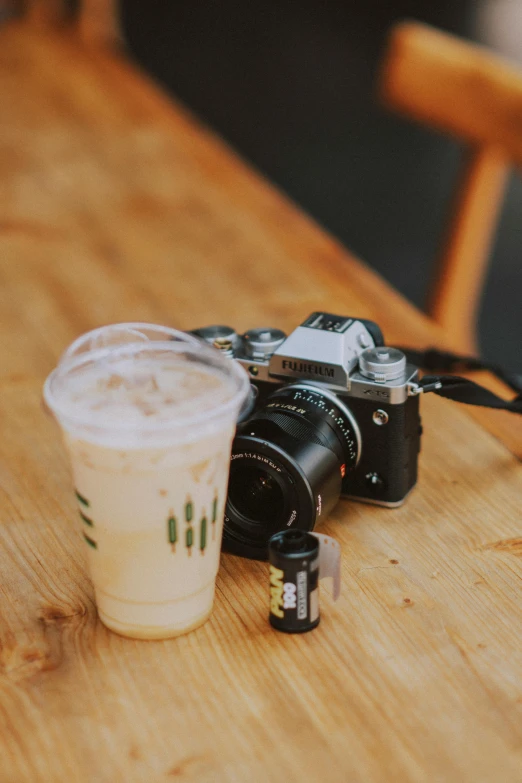 the camera is sitting on the table beside a cup