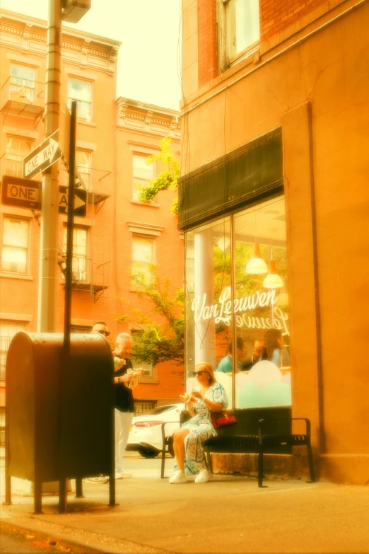 a man sitting at the end of a bench in front of an ice cream shop