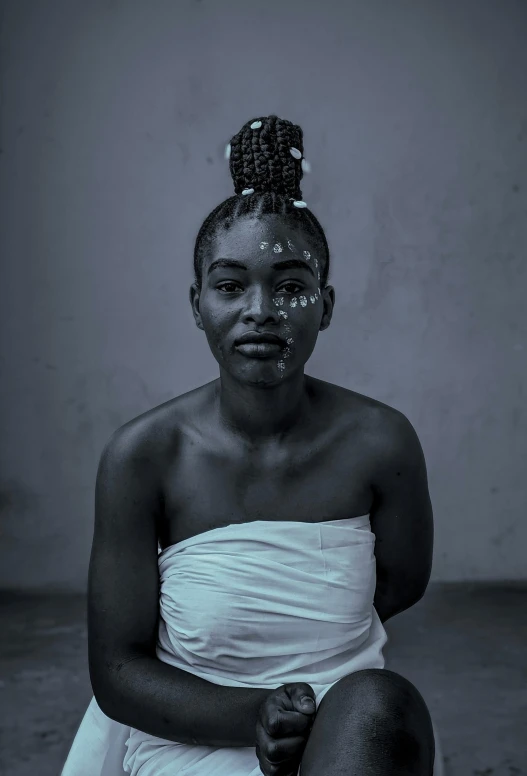 a woman sitting on the ground wearing a white dress and a black face