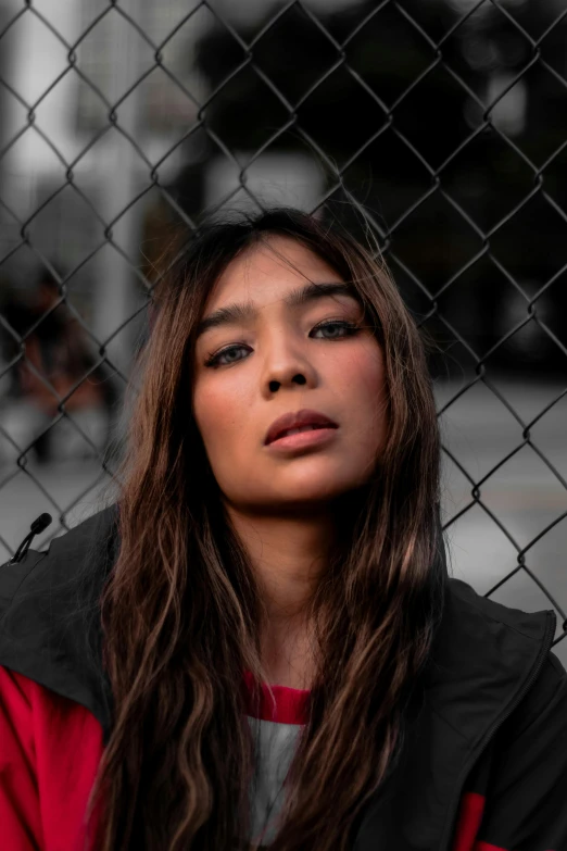 a young woman standing by a fence, looking up