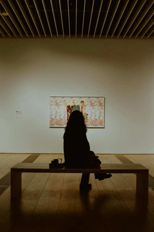 a person sitting on a bench in a large gallery