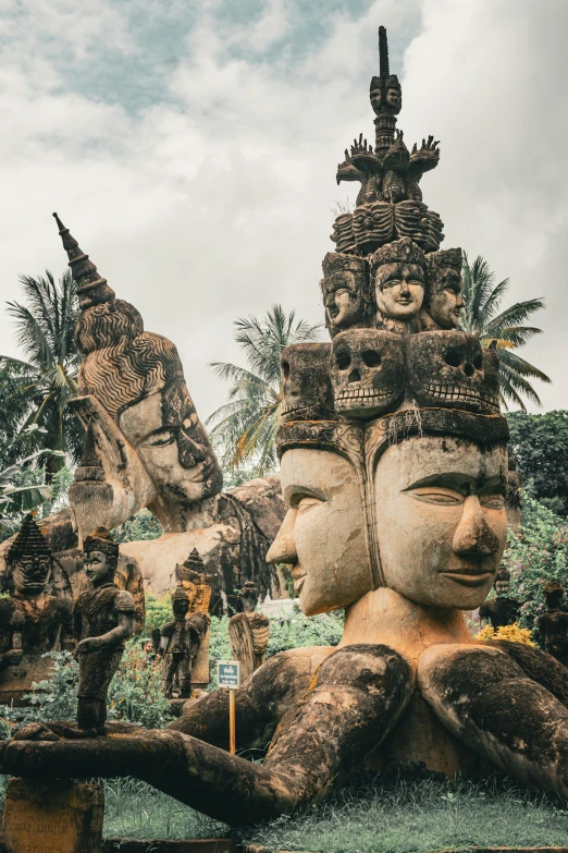 a row of buddha statues sit in front of palm trees