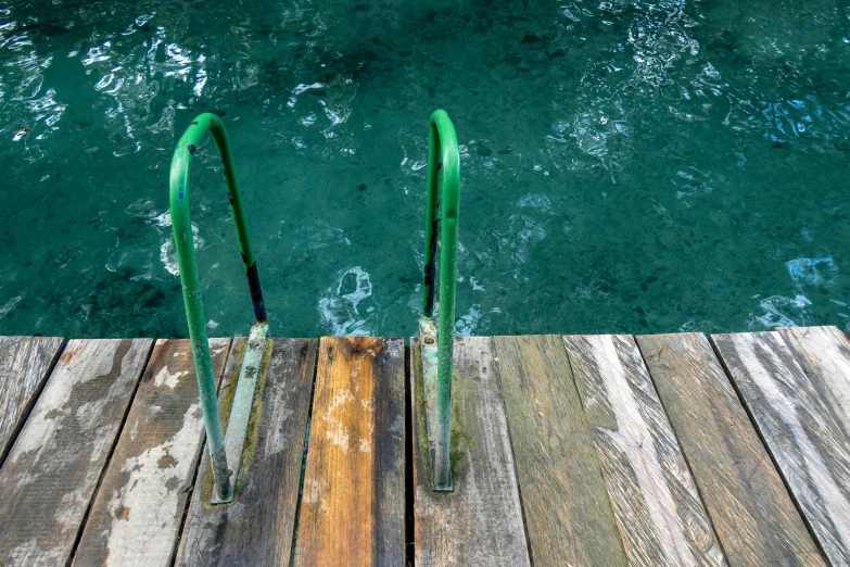 two green railings sit on the edge of a wooden dock