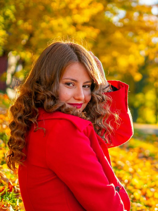 a woman in a red coat leaning against an oak tree