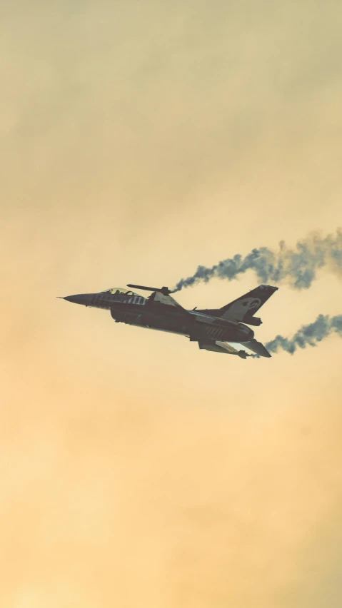 smoke billows from a jet as it flies through the sky