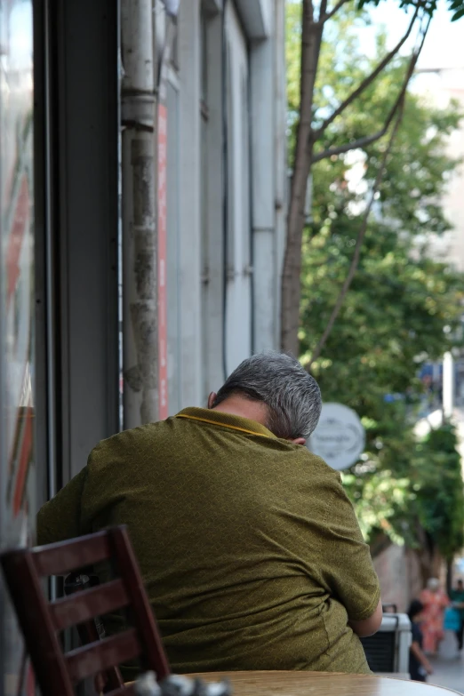 man wrapped up in a blanket sitting at a cafe table