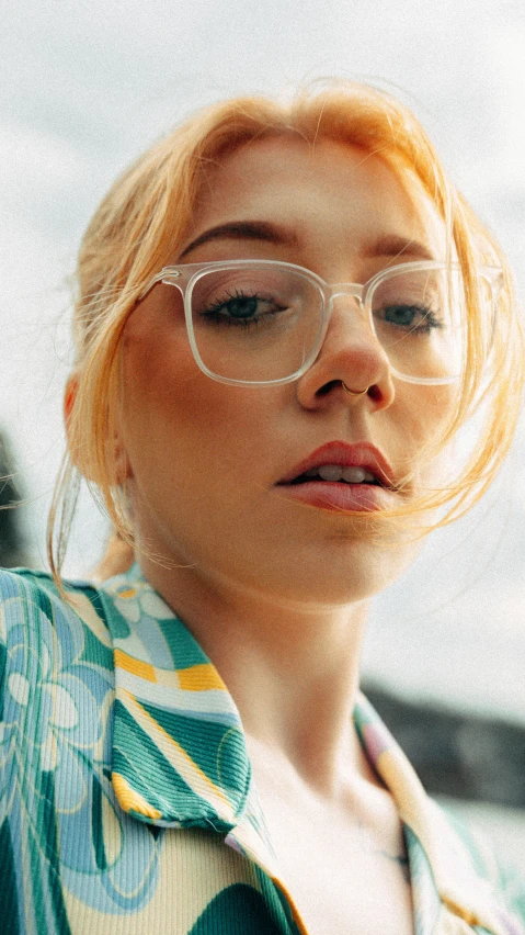 a woman wearing glasses standing in front of the ocean