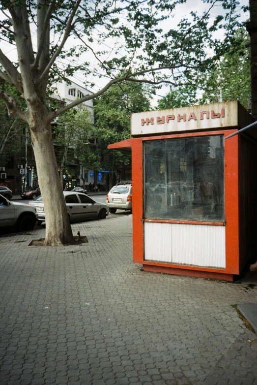 an orange and white phone booth on a brick walk way