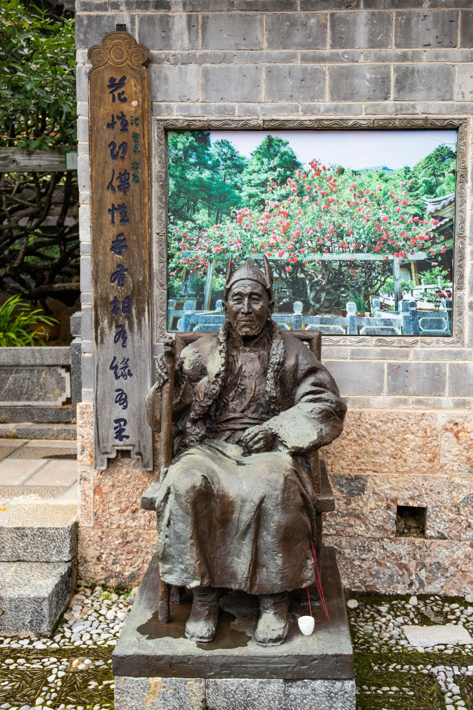 a statue in front of a japanese garden with flowers and foliage