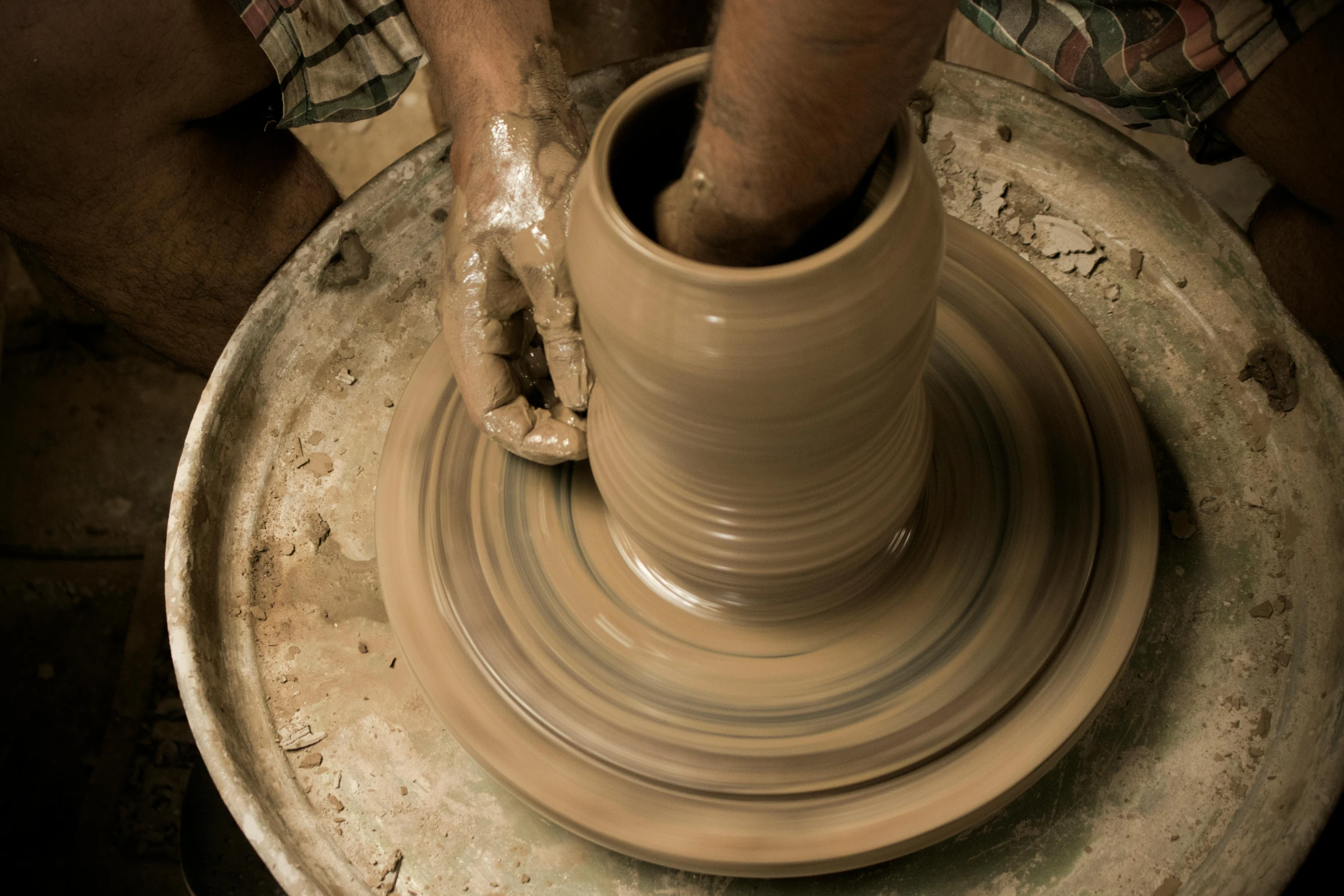 a potter making a clay vessel on a potter wheel