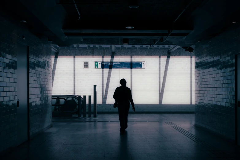 the man in black walking alone inside the dark tunnel