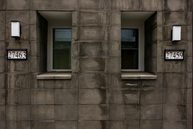 three windows in the side of a building, each have signs on them