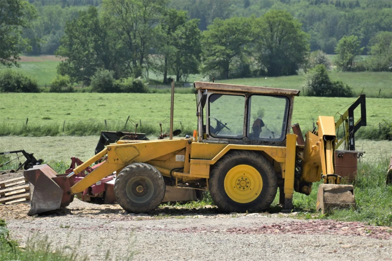 yellow tractor with the back up parked in a field