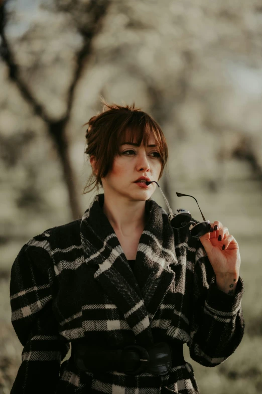 the woman is smoking a cigarette while in a plaid robe