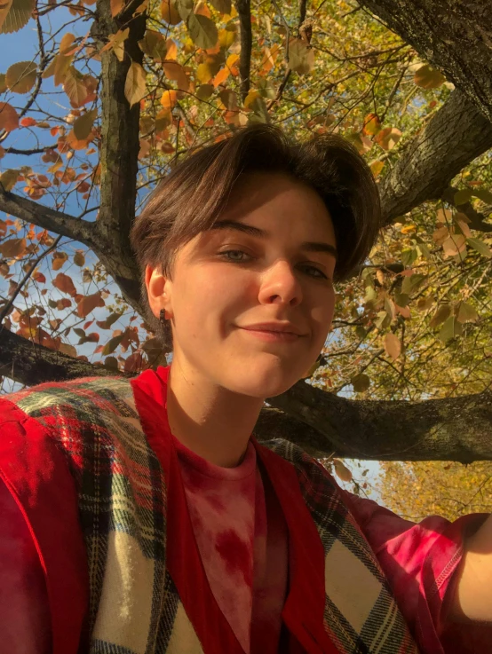 a woman standing under a tree taking a selfie