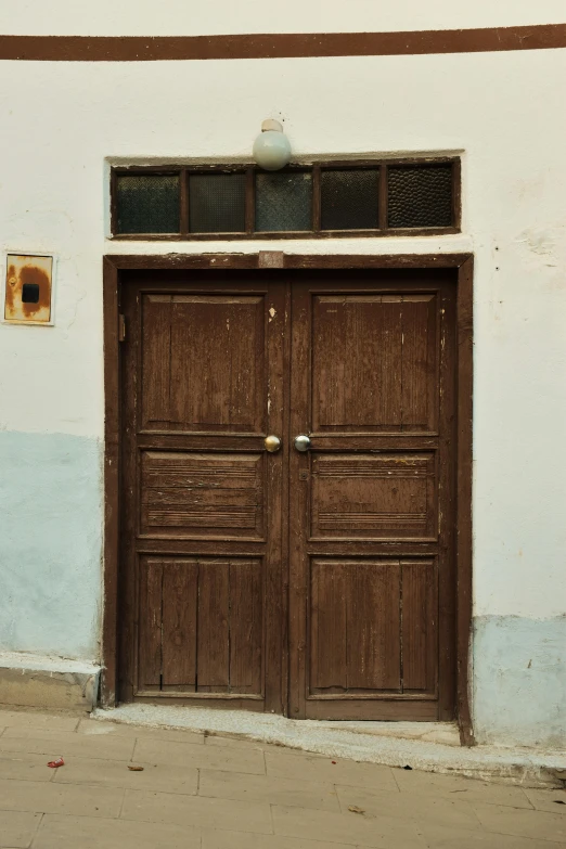 the front entrance of a white building with wooden doors