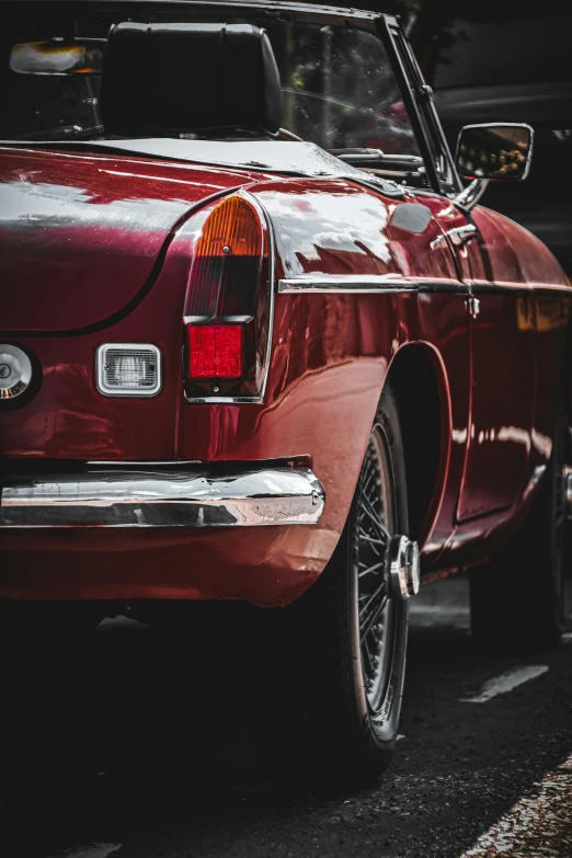 a very pretty old maroon car parked near another old red car