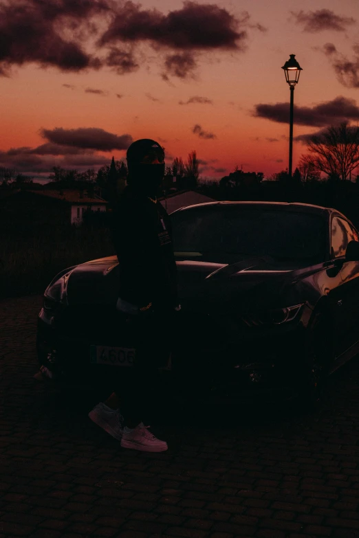 a person is standing next to a car and street light at night