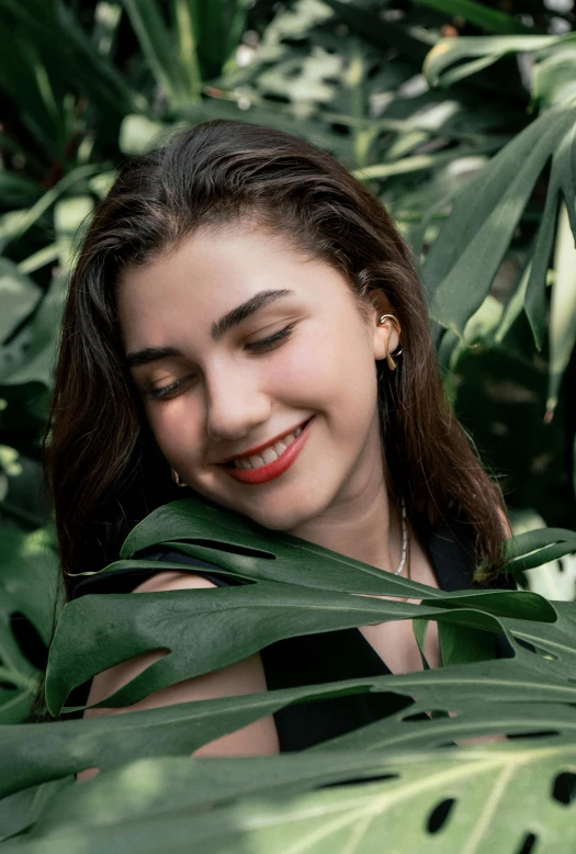 woman in black shirt hiding from foliage with red lips