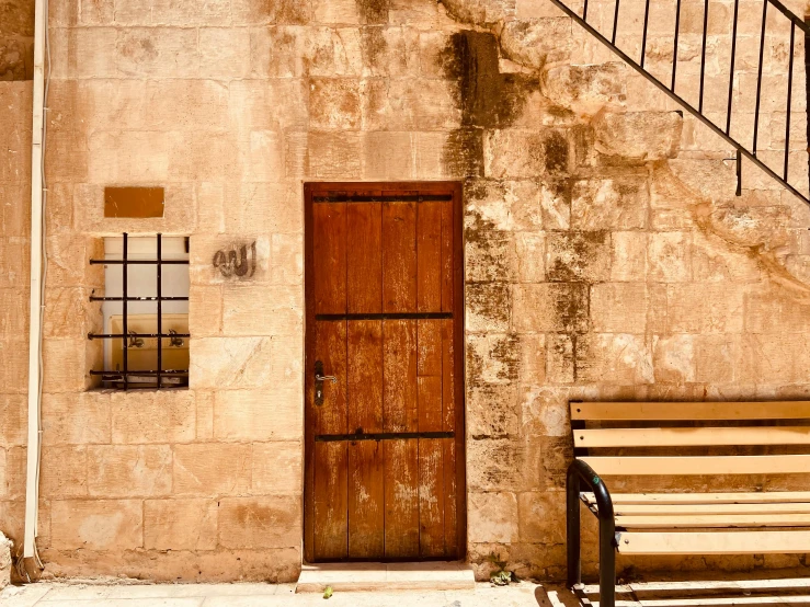 the wooden bench is facing an old concrete building