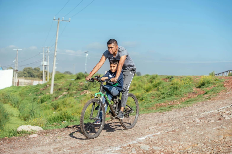 man and boy on a bicycle in the road