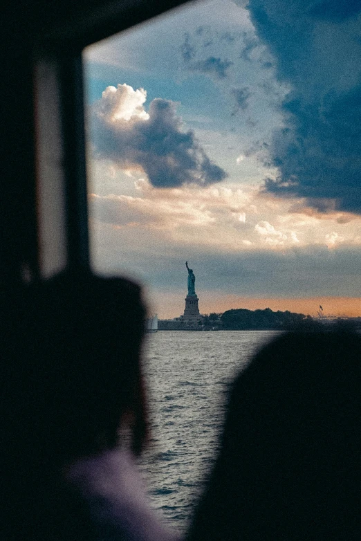 someone is looking out a window at the statue of liberty