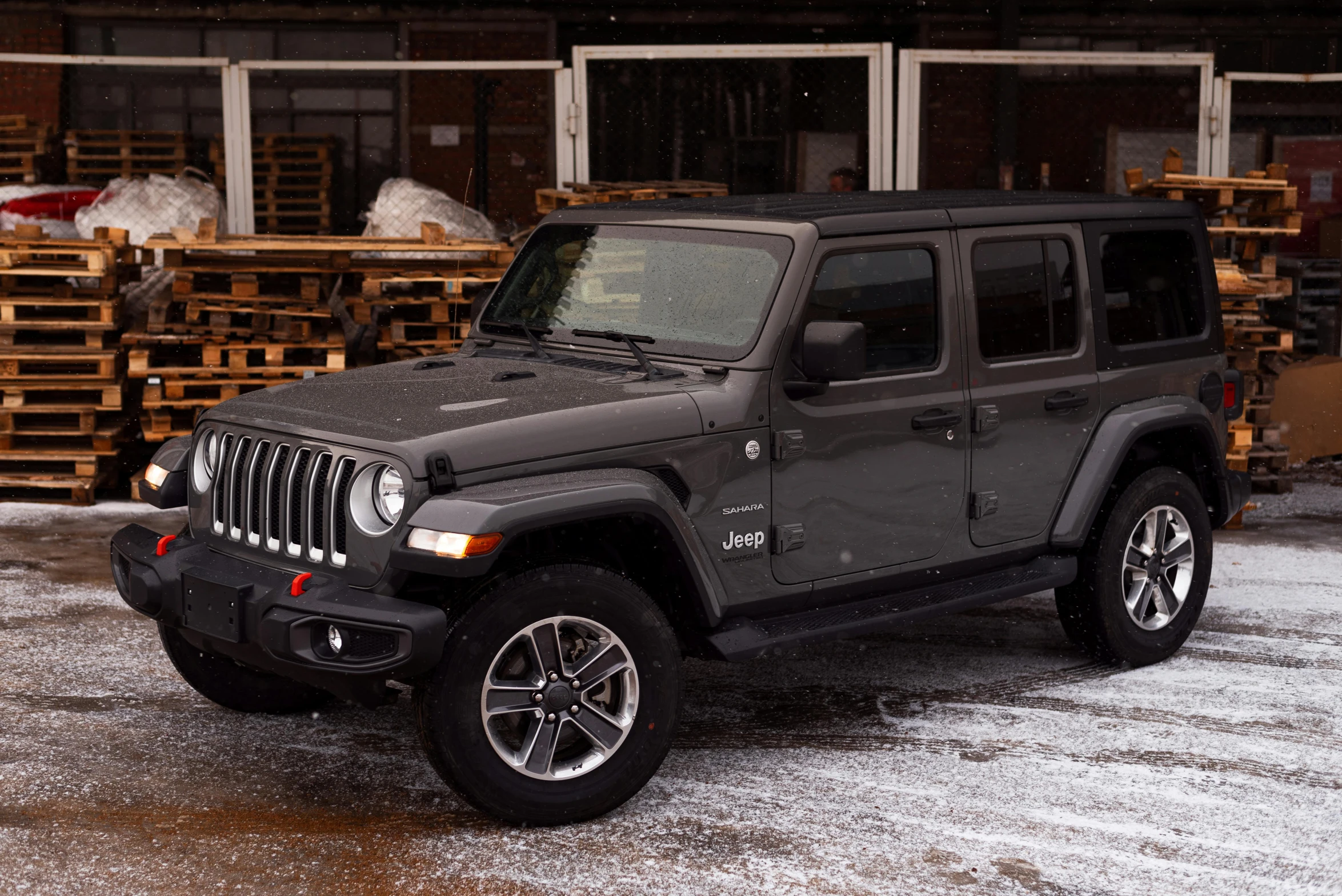 the jeep is parked next to stacked wooden crates