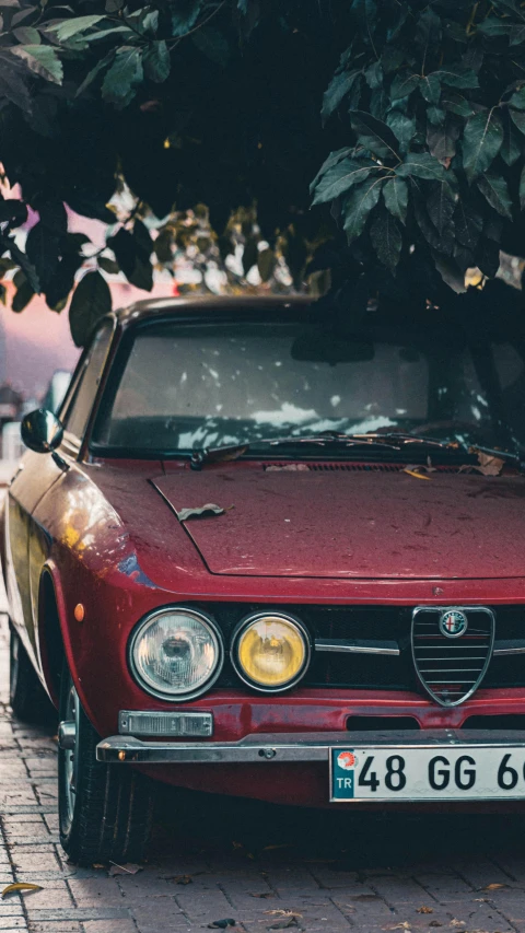 a red alfa coupe parked on the side of a brick road