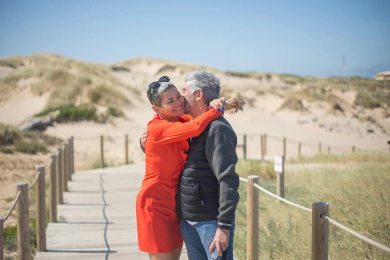 a couple is walking on a boardwalk in the sand dunes