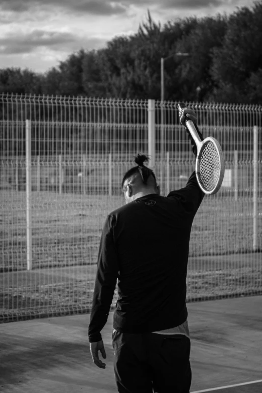 a man holding a tennis racquet over his head on a tennis court