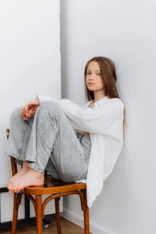 a woman sits on a stool next to her legs crossed